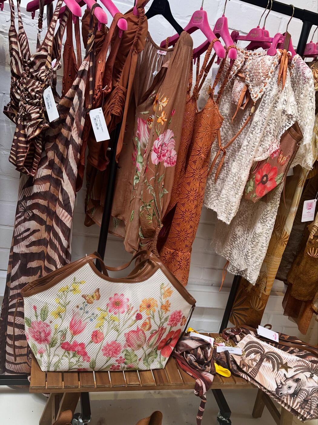 Stender con moda mare in tonalità calde e una borsa a fantasia floreale nella boutique