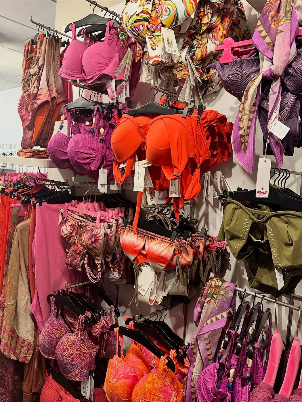 Una parete piena di bikini e costumi interi colorati nella boutique